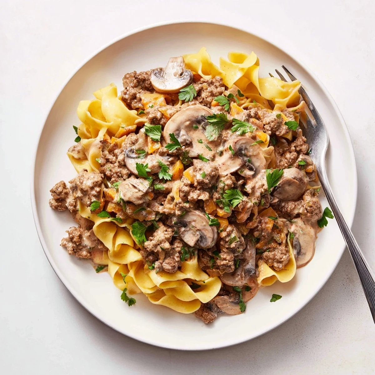 Creamy taco seasoned ground beef stroganoff served over wide noodles, garnished with fresh cilantro.  