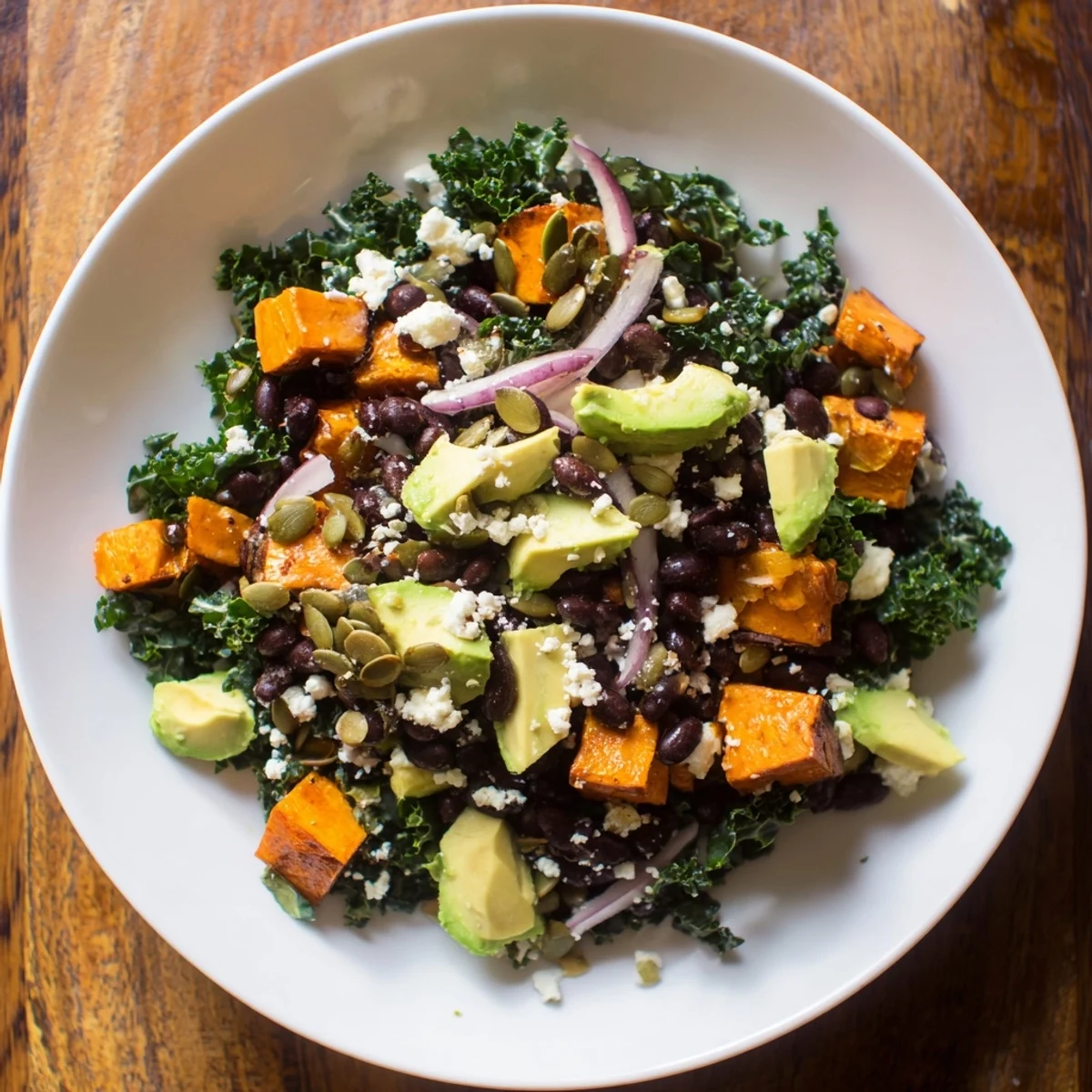 A colorful bowl of massaged kale salad: roasted sweet potato & black beans tossed in vibrant dressing.