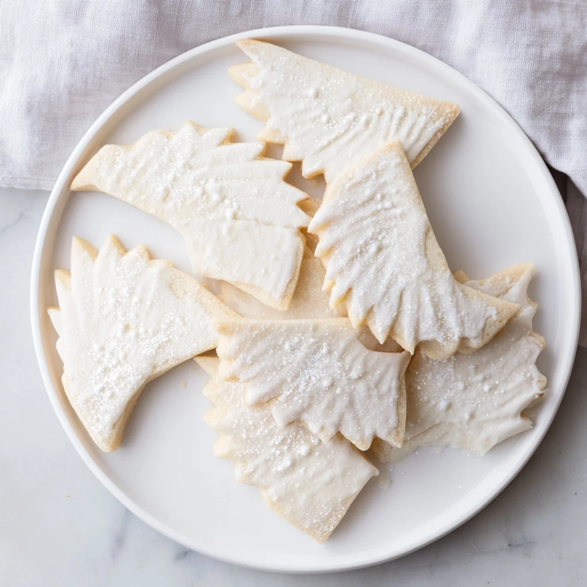 Freshly baked angel wings sugar cookies, golden at the edges, presented on a decorative plate.