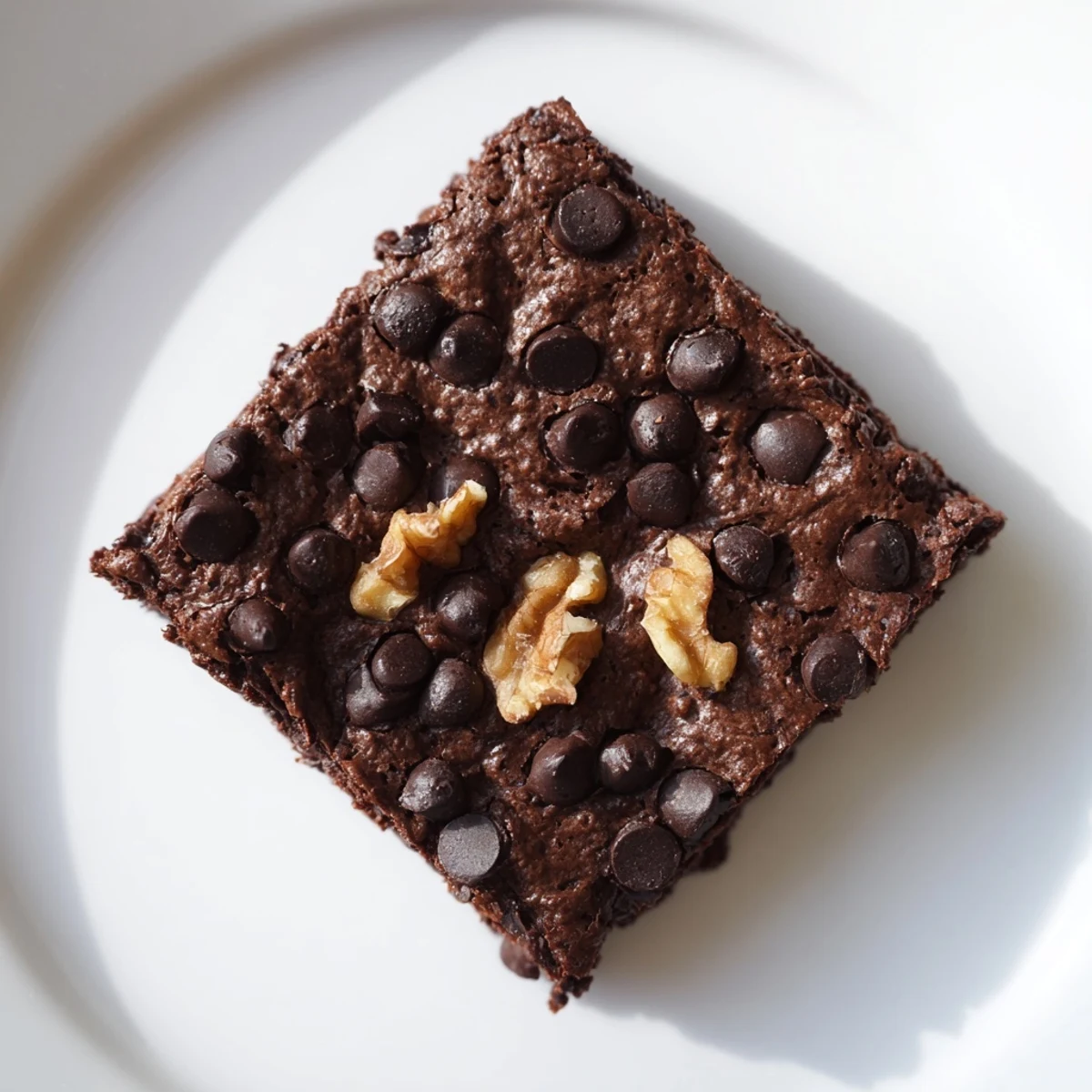 A square of rich, decadent black bean brownie with a fudgy interior and sprinkled chips.