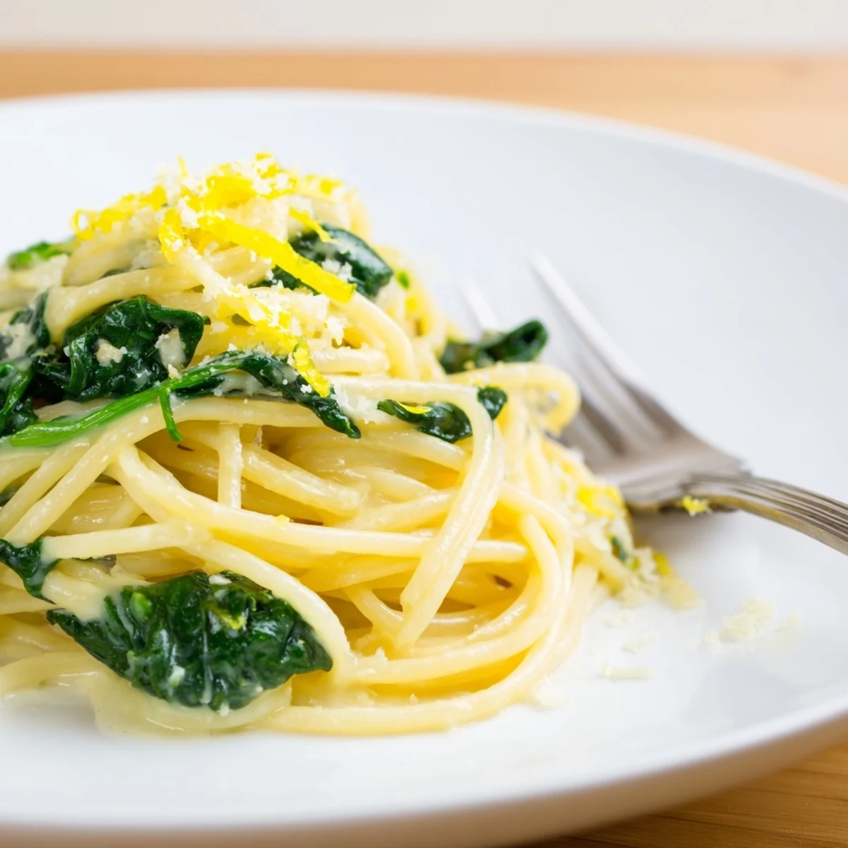 Creamy Lemon Spinach Spaghetti tossed with wilted greens and lemon zest in a skillet, served in a bowl.