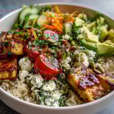 Simple grain bowl topped with grilled chicken, shredded carrots, red onion, and pumpkin seeds, ready for a quick lunch.
