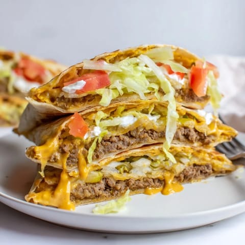 Sliced Crunchwrap Supreme Copycat showcasing vibrant lettuce, cheese, and crispy tostada layers.  