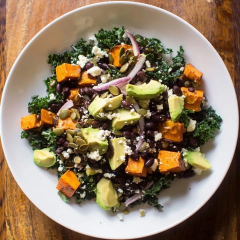 A colorful bowl of massaged kale salad: roasted sweet potato & black beans tossed in vibrant dressing.