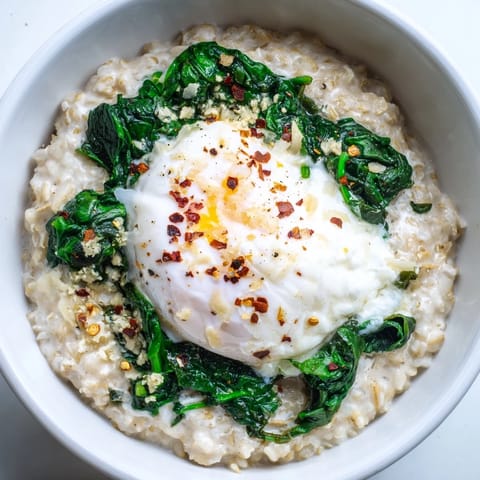 A close-up of savoury oatmeal featuring a perfectly poached egg and vibrant spinach.