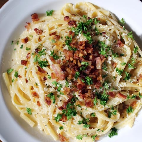 Delicious Garlic Butter Pasta, glistening with sauce and topped with crunchy bacon bits and parsley.