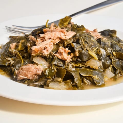 Steaming bowl of Southern style collard greens, with tender greens and savory turkey visible.