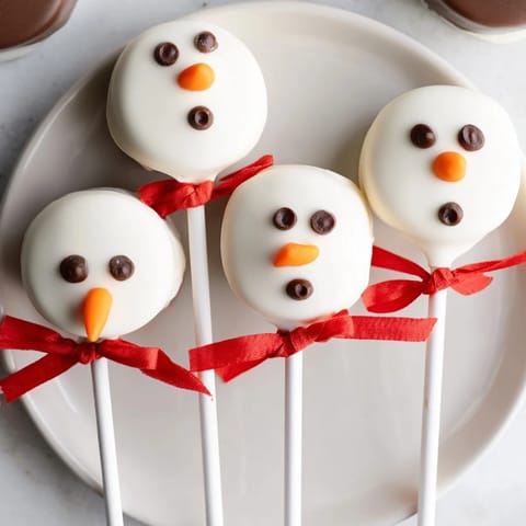 Festive Express Snowman Marshmallow Pops with dark chocolate faces and colorful candy scarves, a delicious dessert.