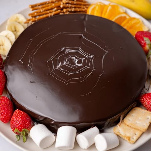 Dippers surround this Spiderweb Chocolate Ganache Board, displaying a sweet Halloween dessert, perfect for sharing.
