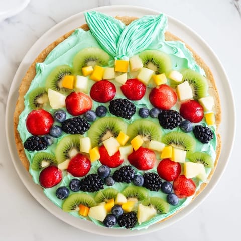 A delicious close-up of the finished Under the Sea Mermaid Tail Fruit Pizza with various fresh fruit pieces.