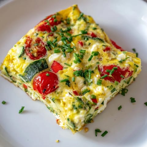The finished High-Protein Sheet Pan Eggs With Cottage Cheese and Veggies cut into squares on a wooden board.  