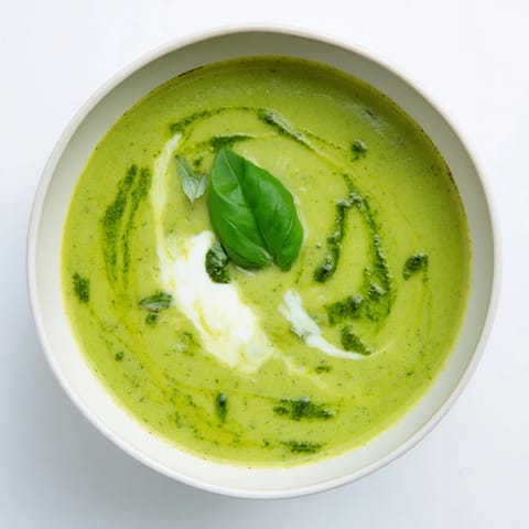 Vibrant courgette, pea and pesto soup swirled with basil, perfect for spring.