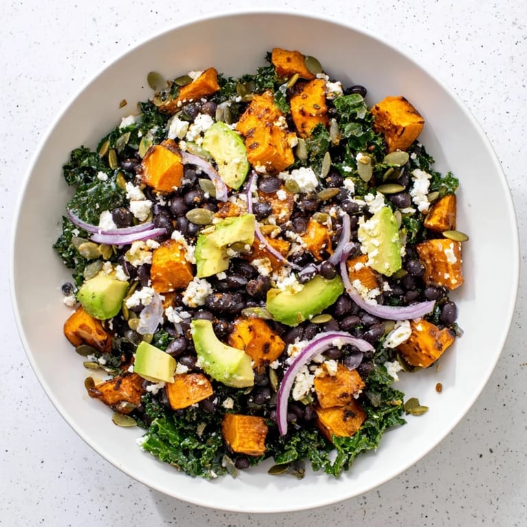 Close-up of hearty massaged kale salad with creamy avocado, sweet potato, and black beans ready to enjoy.