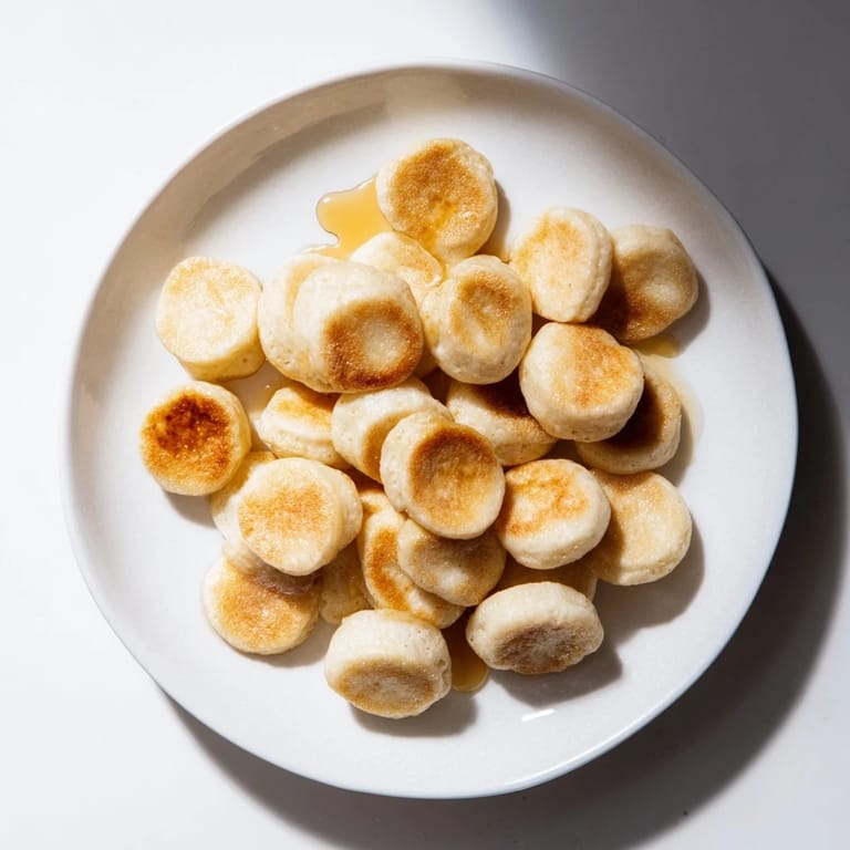 Mini pancake cereal, tiny golden pancakes piled high, ready to be drizzled with maple syrup.