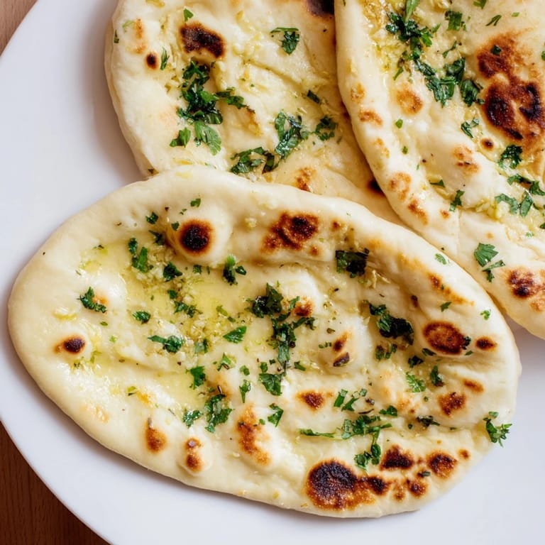 Freshly baked Homemade Garlic Naan Bread, wonderfully fluffy and ready to be torn and dipped.
