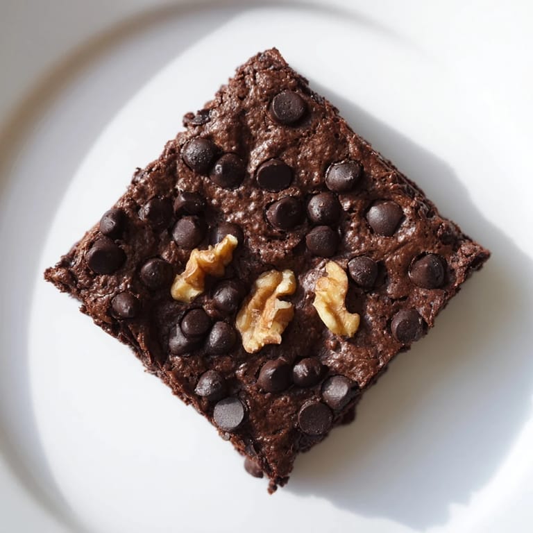 A square of rich, decadent black bean brownie with a fudgy interior and sprinkled chips.