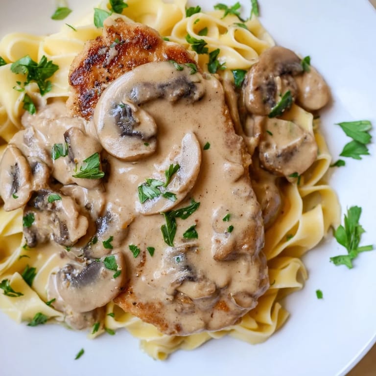 Juicy chicken and cremini mushrooms in a velvety Marsala cream sauce, plated with fettuccine and topped with fresh parsley.