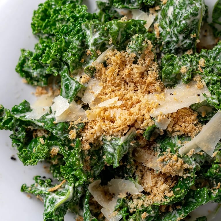 Savory Garlic Parmesan Kale Salad served on a white plate with shaved Parmesan garnish.