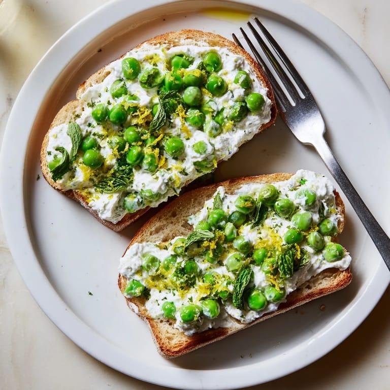 A close-up of bright pea and mint ricotta toast, garnished with lemon wedges for a zesty, refreshing flavor.