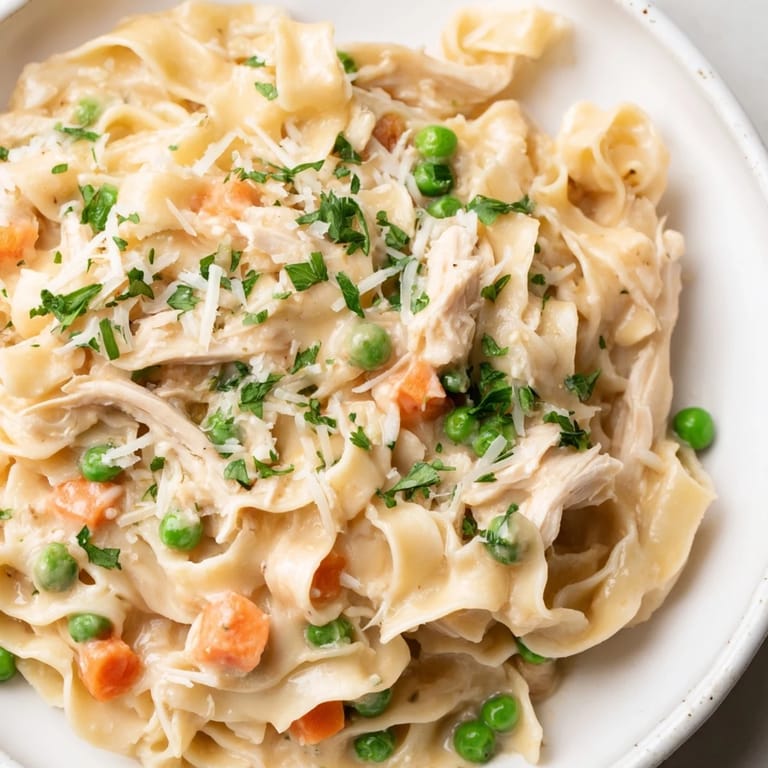 In a rustic skillet, sautéed onions and carrots mingle with peas and Parmesan, creating a comforting, family-friendly Spring Chicken Noodle Skillet ready in 35 minutes.